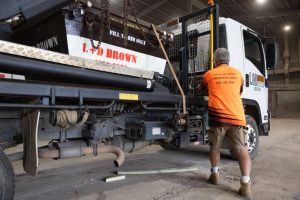 Employee of L & D Brown Skip Bin Hire Loading a Skip Bin in Central Coast
