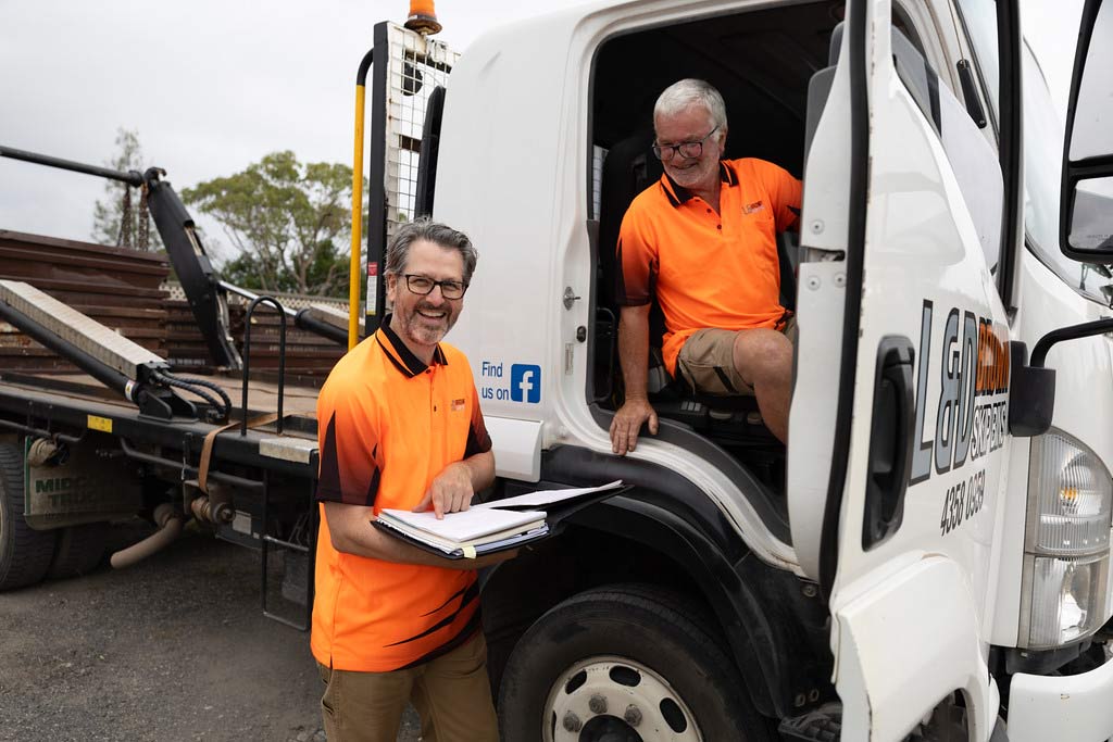 Construction Workers Reviewing Logistics Near Truck