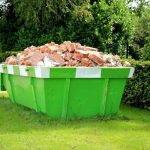 Green dumpster with broken bricks